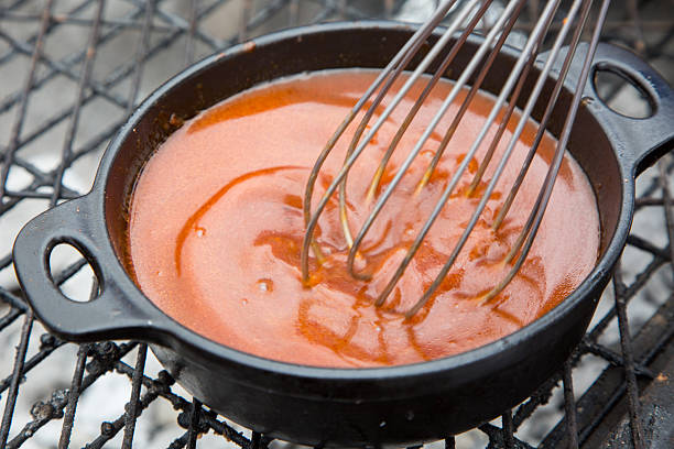 Hot soup placed on the grill while someone stirs it with a hand whisk