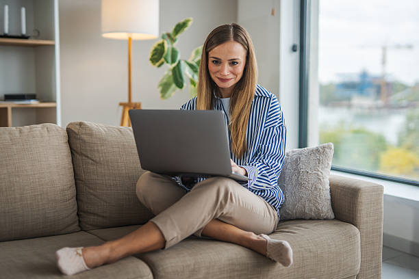 istock Woman working remotely on laptop at home while lying on sofa 2248623582