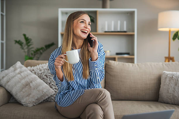istock Woman talking on phone smiling and drinking coffee at home 2248623625