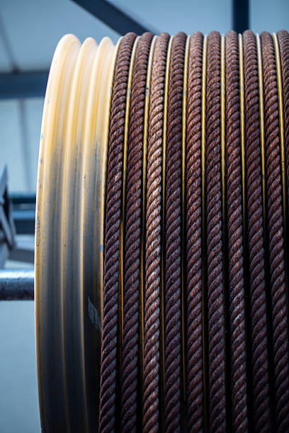 This stock photo features a large, heavy-duty marine rope tightly coiled around a massive industrial spool, highlighting the strength and durability required for maritime operations. The thick rope fibers and rugged texture showcase the materials typically used on cargo ships, docks, and offshore vessels. Perfect for themes related to marine equipment, shipping industry, nautical tools, heavy machinery, and industrial environments. real photo