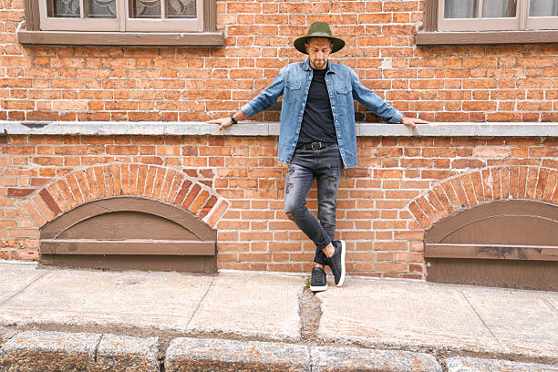 A casual young man standing by a brick ball