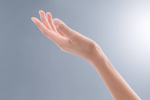 Close-up of an open hand with fingers extended against a neutral gray background, representing care, support, and welcoming gesture.