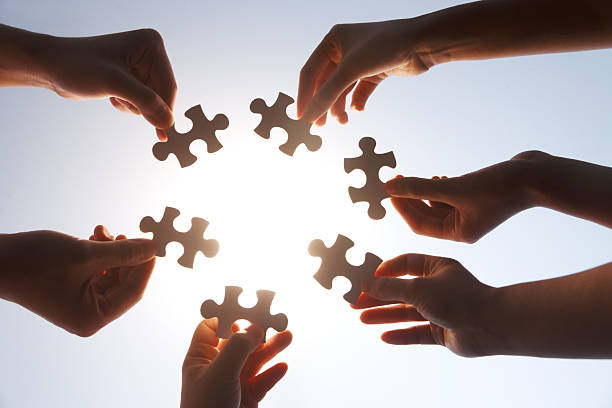 istock Team Holding Jigsaw Puzzle Pieces Together Against Sky 2248626293