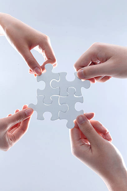 istock Four Hands Holding White Jigsaw Puzzle Pieces Together 2248626349