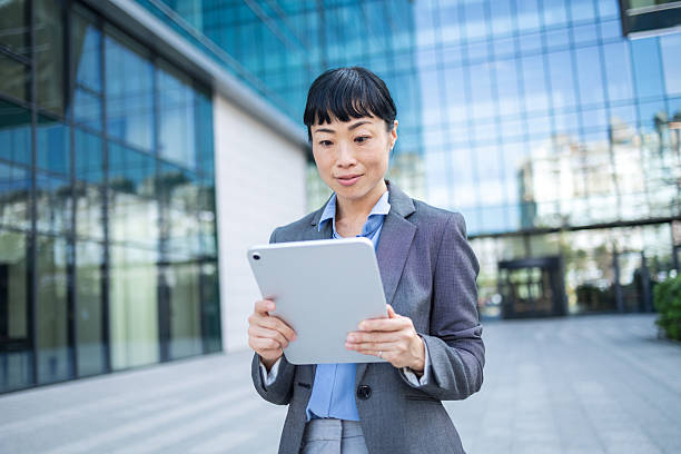 istock Asian businesswoman using digital tablet in front of office building 2248626875