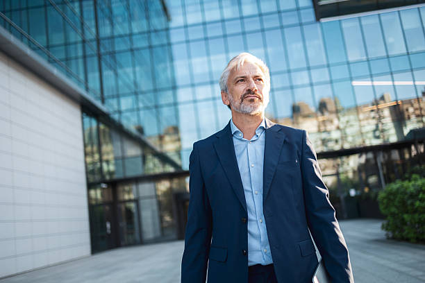 istock Mature businessman standing outside modern corporate building looking forward 2248626995