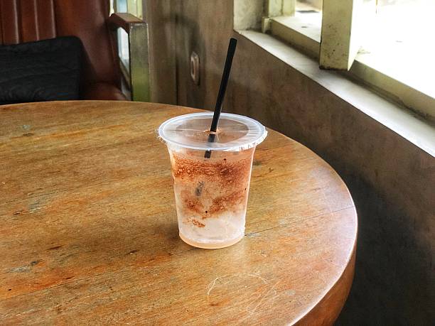 Refreshing cold drink in a plastic cup with a black straw, placed on an aesthetic wooden table