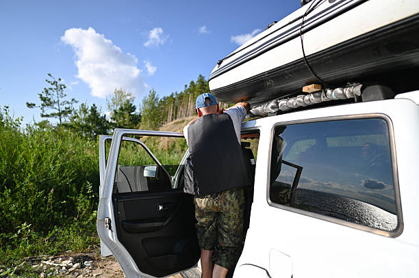 istock Man preparing inflatable boat on suv roof rack for adventure 2248630222
