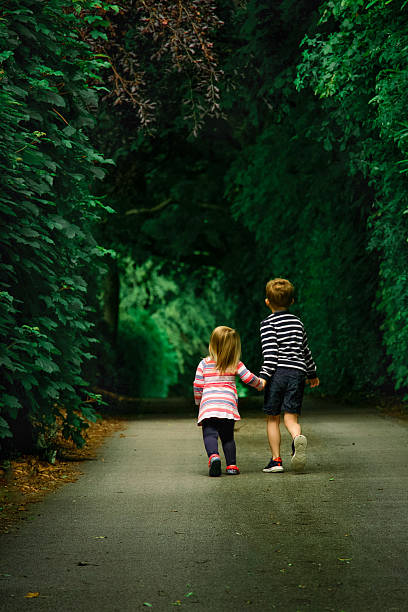istock Siblings walking hand in hand along a leafy forest path 2248630710