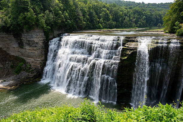 istock Lush green landscape surrounding a beautiful waterfall cascading down rocky cliffs into a serene lake on a clear sunny day in nature's embrace 2248634992