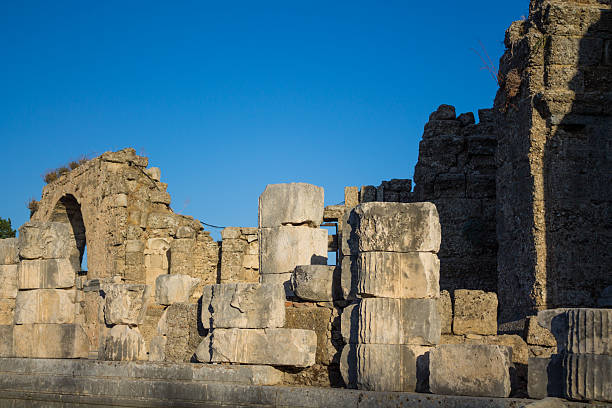 Side ancient ruins in Turkey with stone columns, historic architecture, archaeological site structures, weathered marble blocks, cultural heritage landmark, Mediterranean landscape and clear sunlight