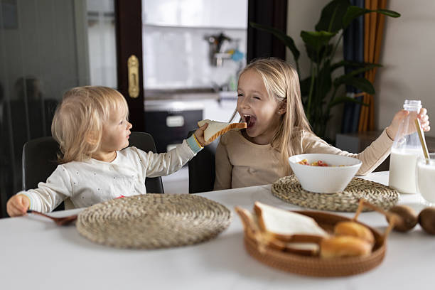 istock Cute caucasian siblings sitting at table on kitchen early morning and preparing breakfast with colorful cornflakes and milk. Kids enjoying life with healthful food, healthy lifestyle concept 2248638960