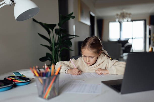 istock Caucasian kid studying online at home and using laptop. Distance or remote learning for child. Pretty stylish schoolgirl studying homework math during coronavirus covid-19 quarantine and social distancing 2248640884