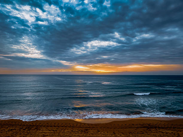 Sunrise Seascape with rain clouds at Bilgola Beach on the Northern Beaches of Sydney, NSW, Australia.