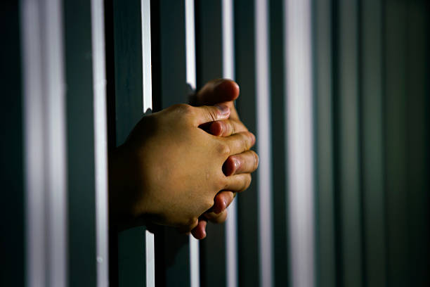 istock Hands Grasping Metal Bars in Dark Setting with Shadow Play 2248652315