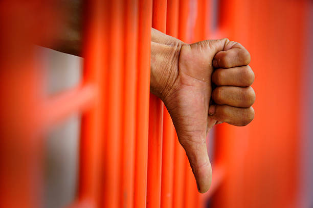 istock Hand Showing Thumbs Down Gesture Through Orange Metal Bars 2248652393
