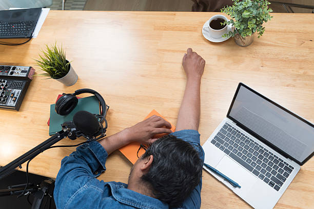 istock Tired man sleeping on work desk with laptop, microphone and headphones showing creative burnout concept 2248654881