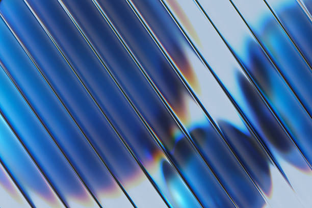 A close-up abstract image featuring glass strips arranged diagonally and blue round shapes behind it. Light creates rainbow reflections and glossy highlights, suggesting modern design, technology, and futuristic aesthetics.