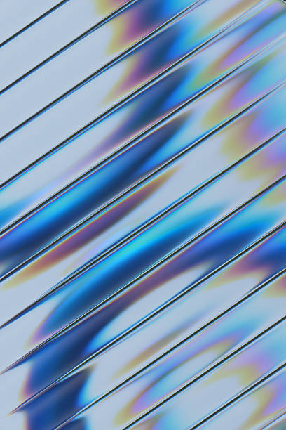 A close-up abstract image featuring glass strips arranged diagonally and defocused blue rings behind it. Light creates rainbow reflections and glossy highlights, suggesting modern design, technology, and futuristic aesthetics.