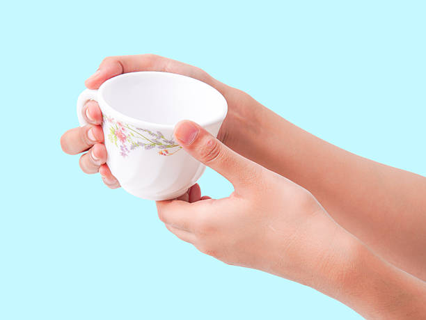 istock Two hands gently hold a floral patterned teacup against a serene blue 2248659511