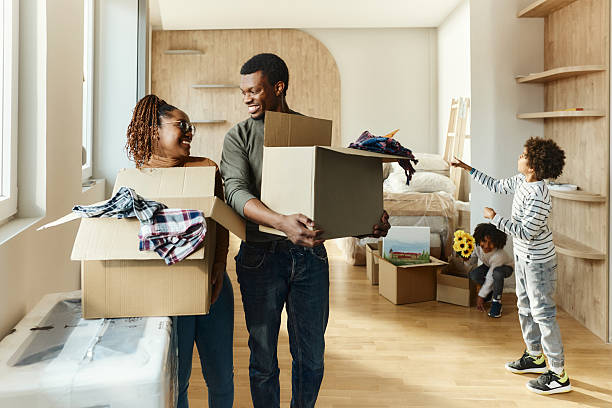 istock Happy black parents talking while carrying boxes in a new apartment. 2248659535