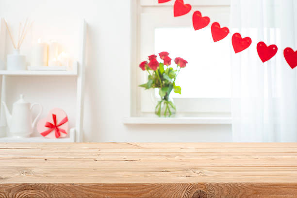 istock Valentine day empty wooden table on decorated with red hearts and flowers blurred window interior background 2248660340