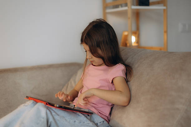 istock Young Girl Engaged in Tablet Use While Relaxing on a Couch 2248660812