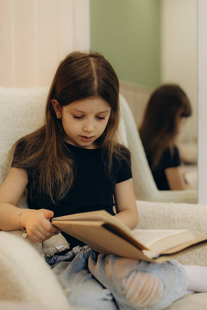 istock Young Girl Reading a Book While Relaxing Indoors in a Cozy Setting 2248660820