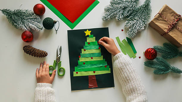 istock Child's handmade Christmas tree craft with ornaments and decorations on a white table 2248661076