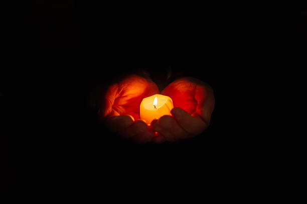 istock Religious concept. Burning candle in the mans hands on a dark background. Religious concept. Selective focus. Copy space. 2248661853