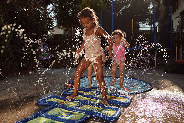 Young girls having fun in backyard with water sprinklers