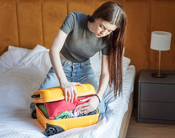 istock Young woman struggling with overstuffed suitcase on bed 2248668249