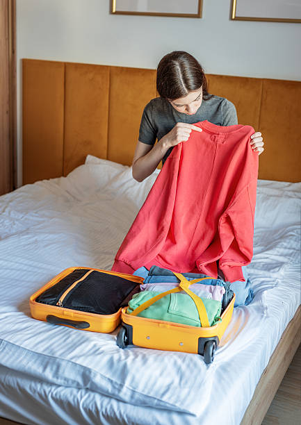 istock Woman packing clothes for travel trip preparing suitcase 2248668254