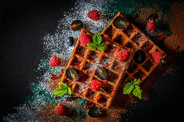 istock Fresh baked chocolate Belgian waffles with raspberries and grapes on black plate for breakfast, closeup, top view. Culinary, cooking, bakery concept. Food recipe background. Sweet waffles with berry 2248668923