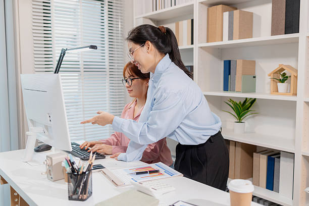 istock Two Asian office colleagues working together in the same department, reviewing documents and discussing project details during a team meeting, showing professional collaboration and teamwork. 2248669997
