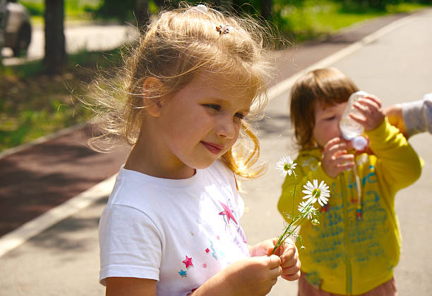 istock Pretty cute sisters having fun outdoors. Sisters walking at springtime enjoying nature, laughing. Baby girl taking a big gulps of water from a bottle, quenching thirst after activities. Happy family 2248671771