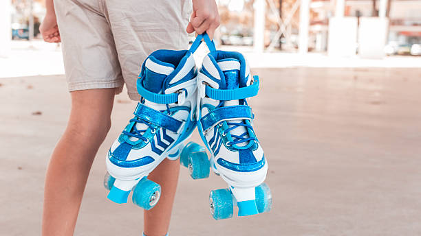 istock Young girl holding blue roller skates with her back to the camera, copy space 2248675405
