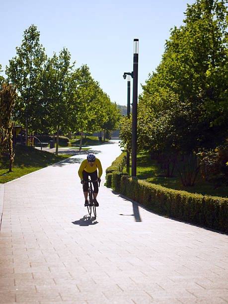 istock Man in yellow jersey riding bicycle uphill on sunlit park path 2248675439