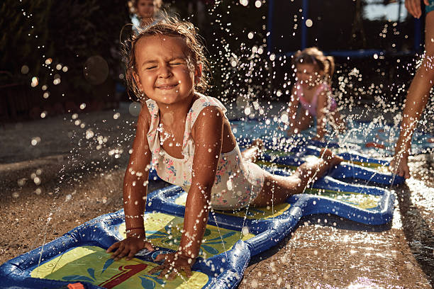 Little girl smiling and splashing water on an outdoor slip and slide