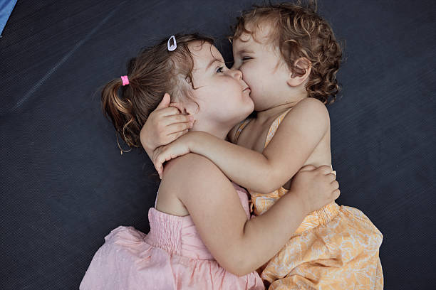 Two young sisters kissing and hugging, showing love and affection