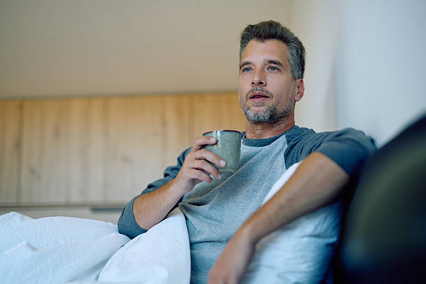 istock Man drinking coffee in bed, enjoying a thoughtful morning routine and relaxed domestic lifestyle at home 2248678928