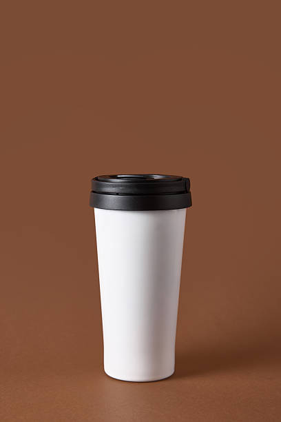 istock White travel mug with black lid on brown background. 2248679541