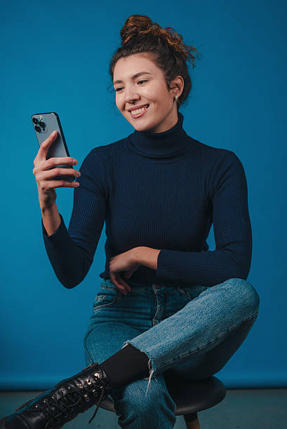 istock woman using phone casually smiling, happy female influencer viewing comments in relaxed setting 2248680131