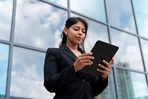 istock Business professional using a tablet outside a modern office building on a sunny day 2248680908