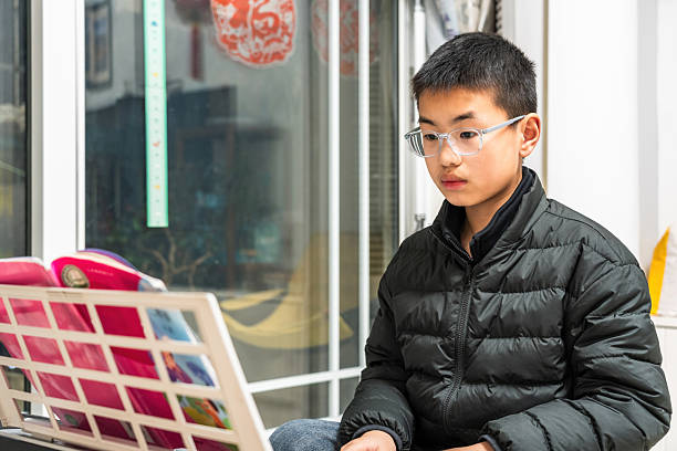 These are two little Asian Boys, about 10 years old. They are brothers, dressed in casual clothes, and are coloring their pottery bowls in a handicraft workshop. They are very happy and serious.