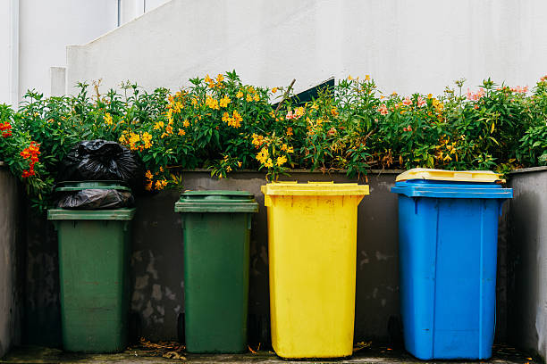 Colorful waste bins in a garden setting surrounded by vibrant flowers, showcasing an eco-friendly waste management system with a focus on recycling and sustainability practices