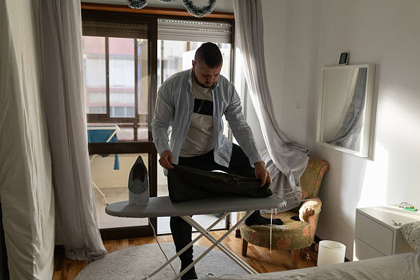 istock Man ironing clothes on board in bright room 2248684980