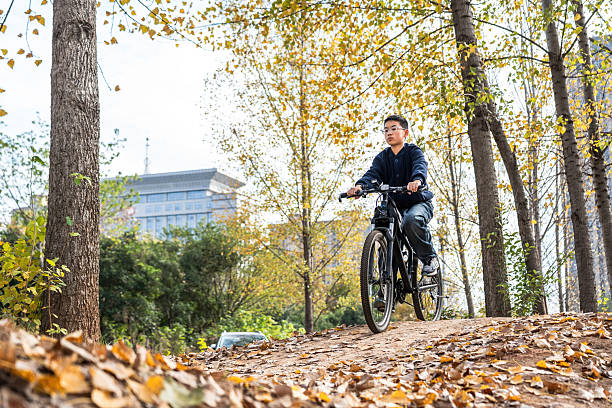 istock Man riding bicycle in autumn forest with fallen leaves 2248685119