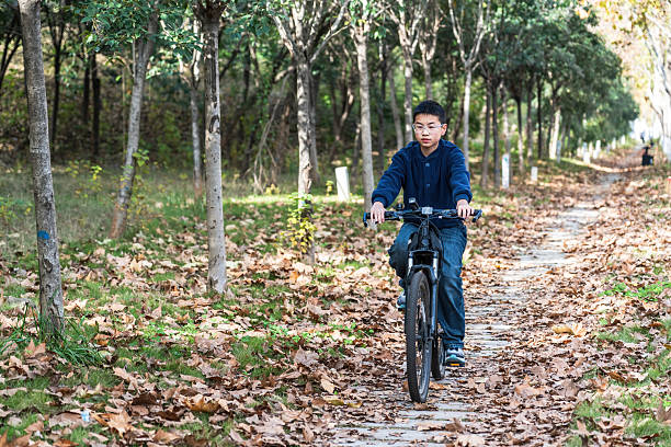 Young man riding bicycle on a path covered with fallen leaves in a forest