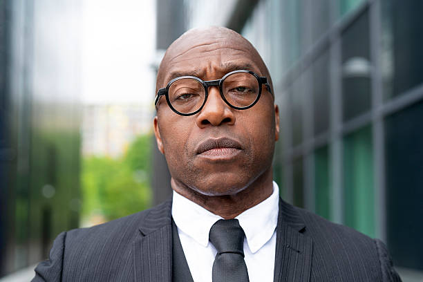istock Confident man in suit with glasses standing outside a modern building on a sunny day 2248685351